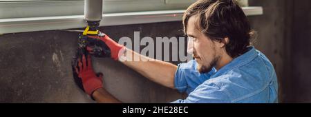 Man in a blue shirt does window installation BANNER, LONG FORMAT Stock Photo