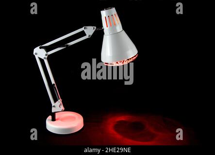 Illuminated infra red health lamp isolated on a black background Stock Photo