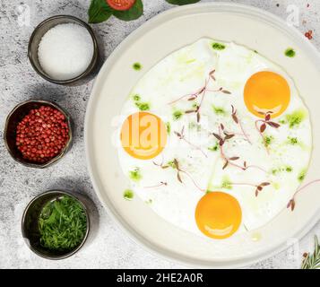 Breakfast. fried eggs from three eggs are sprinkled with grass on a light plate  Stock Photo