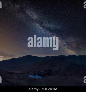 Digital composite image of Milky Way night sky over landscape image of Blea Tarn in Lake District Stock Photo