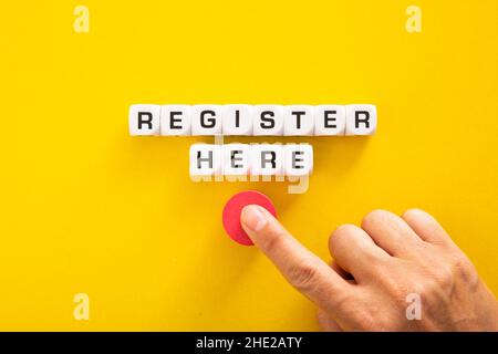 Hand pushing button with Register Here word. Stock Photo