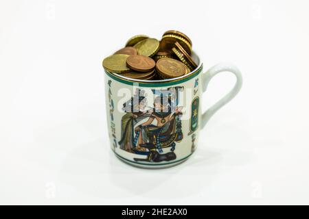 coins in the decorated antique ceramic tea cup Stock Photo