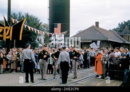 A crowd of supporters turn out on August 9th 1952 at the railroad station in Iowa City, Iowa, USA to await the arrival of Republican Dwight D Eisenhower on his campaign train in that year’s United States presidential election. Placards have slogans on them saying ‘Ike for us’ and ‘Welcome Ike’. Posters of Eisenhower and Richard Nixon, Eisenhower’s running mate, are on show.  Eisenhower won a landslide victory over Democrat Adlai Stevenson. This image is from an old American amateur Kodak colour transparency – a vintage 1950s photograph. Stock Photo