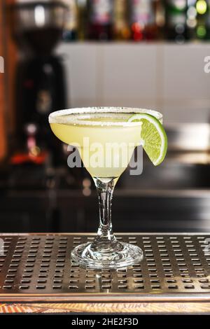 Classic lime margarita cocktail with tequila, lime juice, crushed ice and a little salt on the edge of the glass, garnished with a slice of lime. Stock Photo