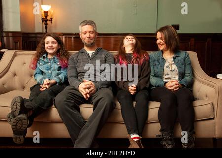 a happy family sitting on their couch having a good hard laugh at something Stock Photo