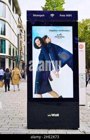 The shopping boulevard Königsallee in Düsseldorf/Germany with modern digital advertising wall / bluespot Free WiFi. Stock Photo