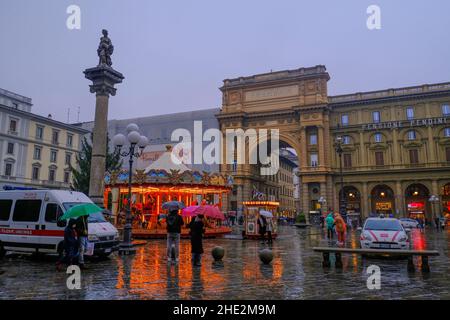 december 2021 Florence, Italy: Piazza della Repubblica, square of Republic, Carousel in lights with kids across arch and The Column of Abundance, and Stock Photo