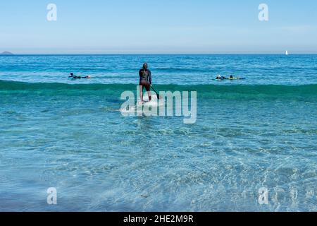 Learning how to stand up paddle in the ocean waves on a sunny clear day in Canary Island Lanzarote Stock Photo