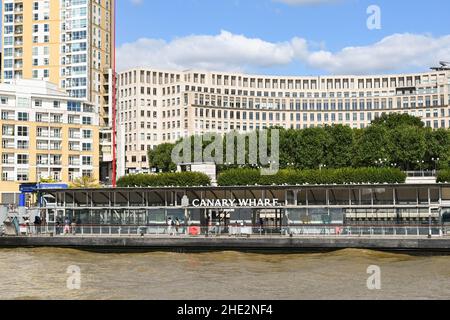 London, England - June 2021: People waiting for a passenger ferry on the jetty at Canary Wharf in central London.