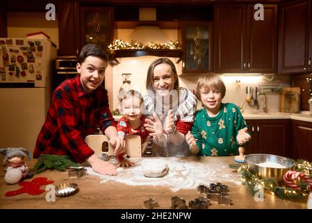 Family with three kids cooking ginger cookies. Merry Christmas, Happy New Year. Family time, preparation for holidays. Stock Photo