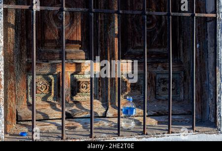 LITTER A DISCARDED PLASTIC WATER BOTTLE PLACED BESIDE A VERY OLD WOODEN WINDOW SHUTTER Stock Photo