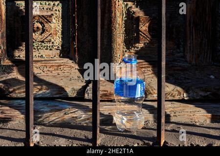 LITTER A DISCARDED PLASTIC WATER BOTTLE PLACED BESIDE AN OLD WOODEN WINDOW SHUTTER Stock Photo