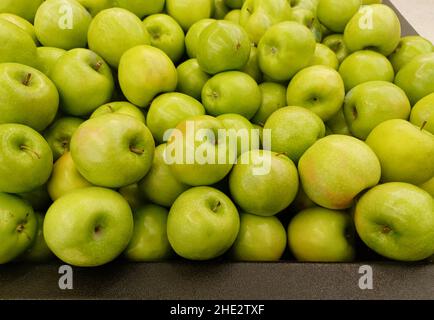 Ripe Granny Smith apples loosely scattered in a traditional vegetable market display, closeup image. Stock Photo