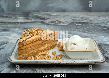 A slice of walnut cake and ice cream in a porcelain serving plate on a marble floor Stock Photo