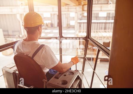 Male worker sitting in operator cabin of overhead crane Stock Photo