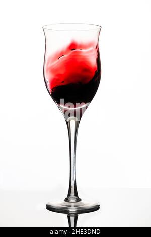 Swirl or movement of liquid in a glass of red wine. White background, vertical orientation. Concept of movement, elegance, taste. Stock Photo