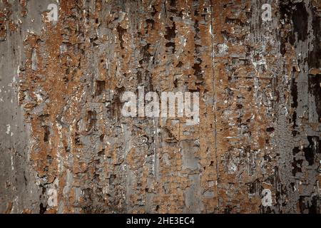 Abstract faded yellow texture with cracks and peeling paint on a wooden door. Stock Photo
