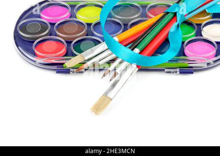 Watercolor paints and brushes isolated on white background. Top view. Free space for text. Stock Photo