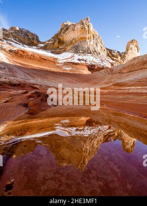 A rare occurrence, snow on red rocks reflected in water in an alcove at White Pocket area of Vermilion Cliffs National Monument, Arizona. Stock Photo