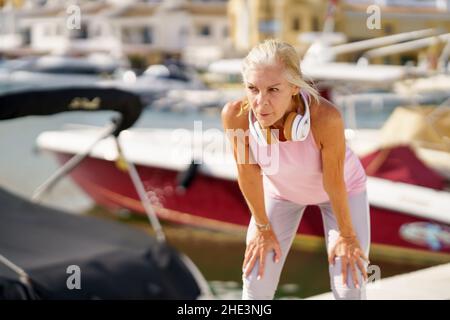Mature sportswoman in fitness clothing taking a break during exercise. Stock Photo