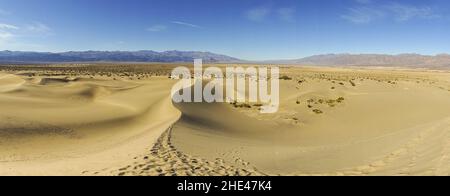 Scenic Panorama of Mesquite Sand Dunes and Arid Desert Landscape with Distant Mountains on Horizon in Death Valley National Park, California USA Stock Photo
