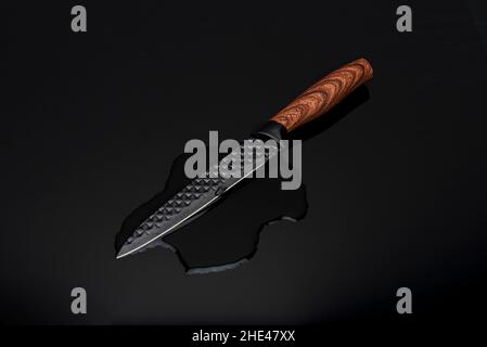 Knife with a wooden handle on the wate on a black surface Stock Photo