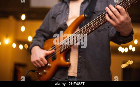 A young guy with a beard plays a bass guitar with five strings Stock Photo