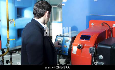 Back view on engineer operating equipment in a factory. Engineer looking at the control panel in a control room of the industrial plant. Back view. Se Stock Photo