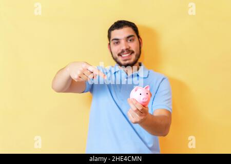 Man holding piggy bank. Close up of finger pointing to a piggy bank. Stock Photo