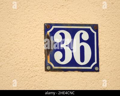 Closeup shot of a blue number thirty six sign on a yellow wall Stock Photo