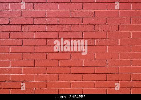 A brick wall is painted in a coat of red paint to create a pattern Stock Photo