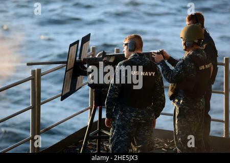 Sailor fires a .50-caliber machine gun at sea. (8382938769). Stock Photo