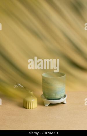 Ceramic tea cup with dry plant on brown table background Stock Photo