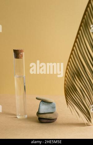 Skincare concept. Stack of pebble stones with tropical leaf on brown table background Stock Photo