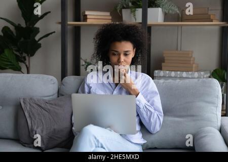 Thoughtful young african american woman using computer. Stock Photo