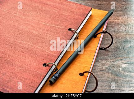 Notepad with wooden cover and a black pencil lying diagonally on desk Stock Photo