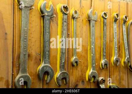Close-up shot of old rusty weathered wrenches of different sizes hanging on a wooden wall Stock Photo