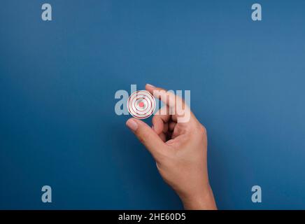 Modern small red target icon symbol in hand on blue. Small business, goal and success concept. Concept of objective attainment and business niche mark Stock Photo