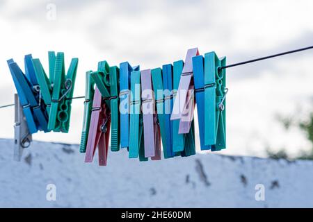 Close-up shot of colorful clothespins hanging on a rope against a blue cloudy sky Stock Photo