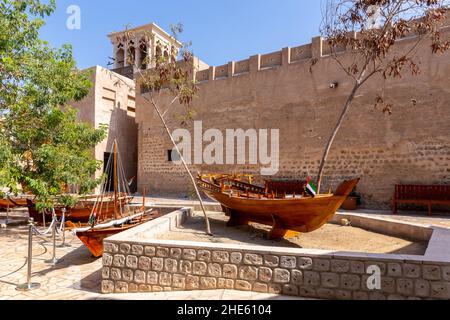 Small traditional wooden rowing boats - abras , with Al Fahidi Old Fort walls in the background, Al Fahidi Historical District, Dubai, United Arab Emi Stock Photo