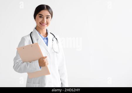 Friendly young cute indian female doctor in uniform with tablet in hands looking at camera isolated on white background Stock Photo