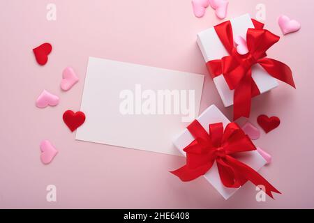 White gift boxes with red ribbon and small red decorative hearts on pink background. Top view with copy space. Valentines day or Wedding romantic conc Stock Photo