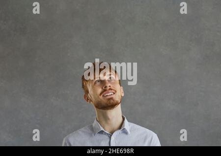 Red-haired young hipster man looking up with dreaming expression on face Stock Photo