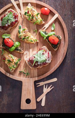 Crisp bruschetta with scrambled eggs and tartare for a snack on a serving board. Stock Photo