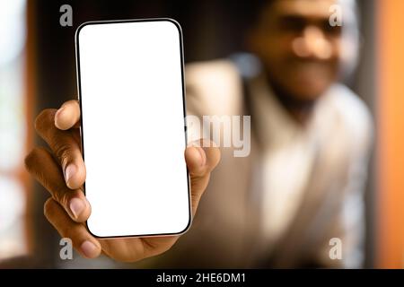 Great offer. Black man showing mew modern smartphone with big white blank screen for app or website design, mockup Stock Photo