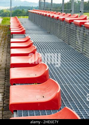 Cheap red stadium seats view. Two rows of simple chairs on tribune Stock Photo
