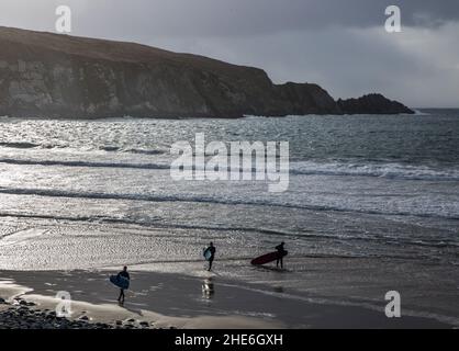 Chimney Cove, Cork, Ireland. 08th Jan, 2022. Three young men carry their boards along the beach after finishing surfing at Chimney Cove, Barleycove, Co. Cork, Ireland. - Picture Credit: David Creedon/Alamy Live News Stock Photo