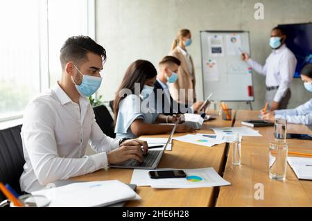 Group Of Multiethnic Colleagues Wearing Medical Masks Having Business Meeting In Office Stock Photo