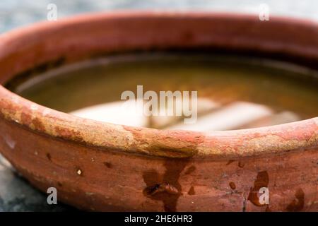 A close up shot of a wide mouth circular clay pot holding water. Stock Photo