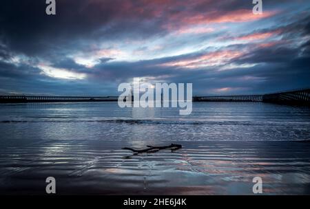 A glorious morning at Blyth beach in Northumberland at sunrise, with a washed up branch on the sand Stock Photo